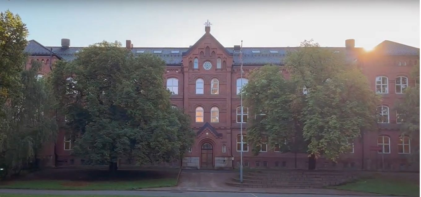 en stor murbygning med trær foran